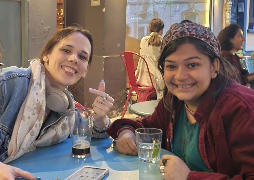 Bidisha Das, PRISM project manager, smiling next to a team member at a café table in Luxembourg City
