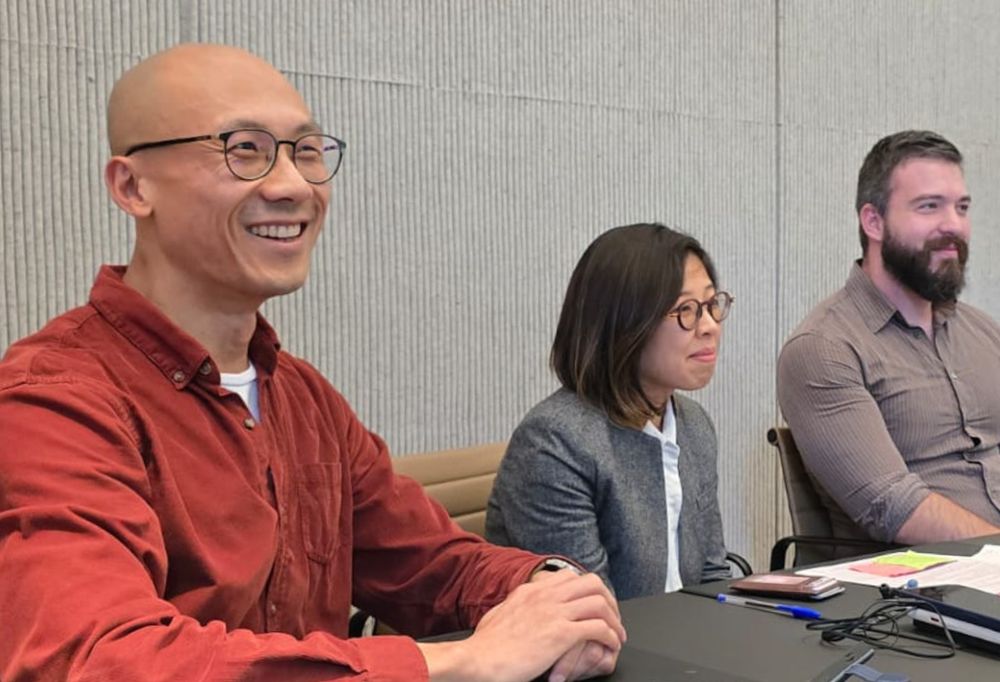 Three Blom members smiling at a table during the Rainbow Career Day panel