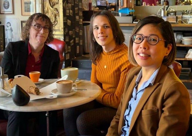 Three members of the Blom team smiling around a café table